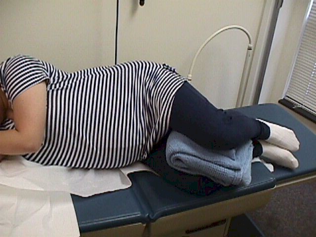 Good sleeping position. Both knees are drawn up with a soft, absorbent blanket between the legs.